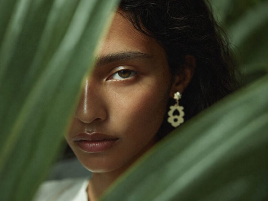 Close-up portrait of a woman framed by tropical leaves.